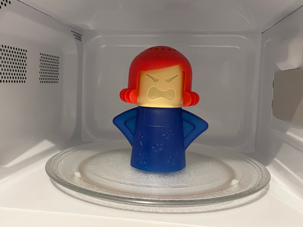 L’Incroyable secret de l’Angry Mama : Ce gadget à 3 Euros va révolutionner le nettoyage de votre micro-ondes ! Figurine nettoyante Angry Mama positionnée au centre d'un four à micro-ondes avant le test